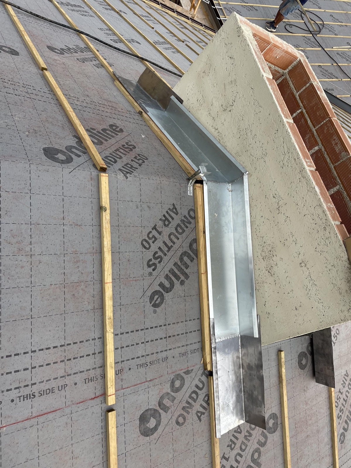 Lima de zinc-titanio alrededor de una chimenea en una cubierta en construcción