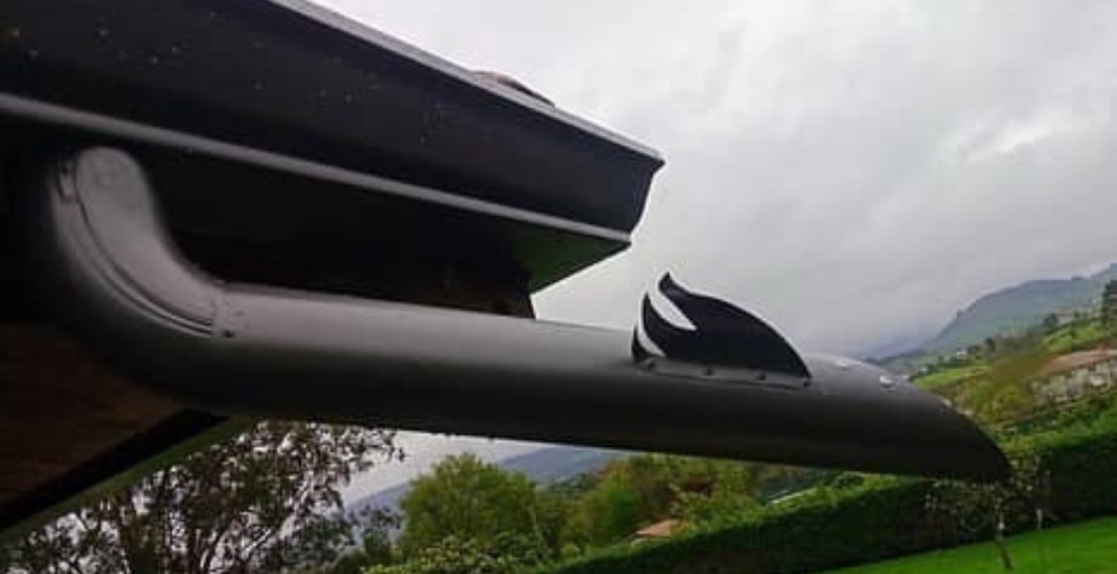 Tapa embellecedora ornamental en un canalón de aluminio negro, con los montes asturianos al fondo